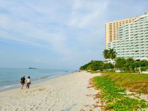 two people walking on the beach next to a hotel at Tanjung Bungah Holiday Home 4BR 20Pax 6Carpark in Tanjung Bungah