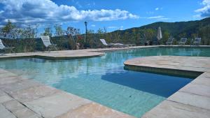 une piscine avec des chaises et des montagnes en arrière-plan dans l'établissement Villa D'Arte Agri Resort, à Pontassieve