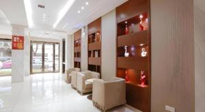 a waiting room with white chairs and a wall with shelves at City Comfort Inn Wuhan Zhongnan Hospital Shuiguohu Metro Station in Wuhan