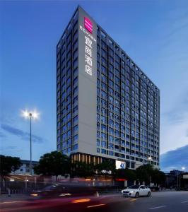 a tall building with a car parked in front of it at Echarm Hotel Nanning Chaoyang Square River View in Nanning