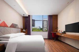 a hotel room with a bed and a television at Borrman Hotel Qianjiang High-speed Railway Station Lobster City in Sanjiang