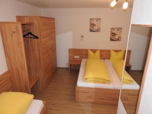 a small bedroom with a bed with yellow pillows at Haus Lydia in See