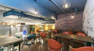 a restaurant with tables and chairs and a brick wall at James Joyce Coffetel Tianjin Railway Station in Tianjin