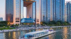a boat in a river in a city with tall buildings at Xana Hotelle Tianjin Binjiang Road Heping Road Metro Station Quanyechang in Tianjin