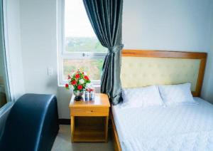 a bedroom with a bed and a window with flowers at Hong Ha Hotel in Pleiku Airport