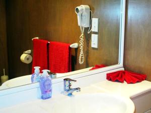 a bathroom with a sink with a mirror and a phone at Muri Beach Hideaway - Adults Only in Rarotonga