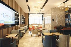 武漢市にあるEcharm Hotel Wuhan High-speed Rail Peace Park Metro Stationのテーブルと椅子、大画面のレストランを併設しています。