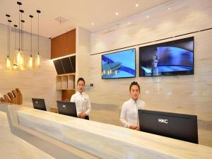 two men standing in a lobby with their laptops at City Comfort Inn Shiyan Wudang Mountain in Danjiangkou