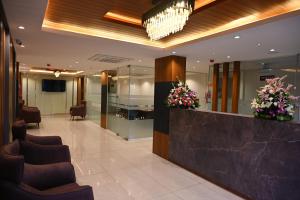 a lobby with a waiting area with chairs and flowers at Good One Suites in Bengaluru