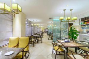 Un comedor con mesas y sillas amarillas. en Dahe Jinjiang Hotel, en Zhengzhou