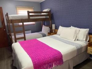 a bedroom with two bunk beds with a pink blanket at Cabañas Bosque Austral in Punta Arenas