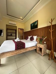 a bedroom with a large bed with a wooden frame at Dukuh Village Villas & Art in Tegalalang