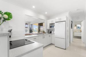 a kitchen with white cabinets and a white refrigerator at Luxury Pool Retreat Ocean & Mountain Views in Scarborough