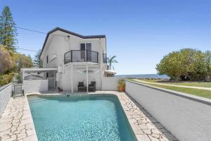a villa with a swimming pool in front of a house at Luxury Pool Retreat Ocean & Mountain Views in Scarborough