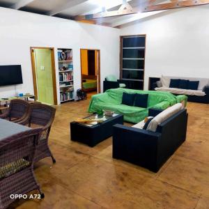 a living room with a green couch and chairs at Mountain Breeze Rarotonga in Rarotonga
