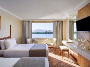 Una habitación de hotel con dos camas y una gran ventana. en Mövenpick Royal Lotus Nile Cruise, Every Monday Four Nights From Luxor, Every Friday Three Nights From Aswan - Including Excursions & Sightseeing, en Luxor