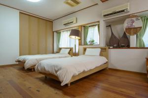 two beds in a room with wooden floors and windows at ようこそ月の宿へ in Shindembaru