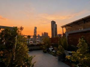 a rooftop patio with a view of the city at sunset at SO Zen Hotel Silom Bangkok in Bang Rak