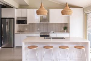 a kitchen with white cabinets and a island with stools at Boomerang Bliss in Elizabeth Beach +18 photos