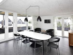 a dining room with a white table and black chairs at Exclusive Golf View Retreat in Rømø Kirkeby