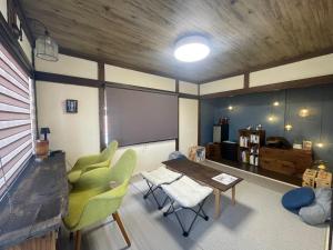 a living room with a table and green chairs at Bear Foot 蒼 in Yakumo