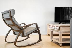 a wooden chair sitting in a living room next to a tv at Comfy Croydon Family Getaway Near Trails and Cafes in Ringwood North