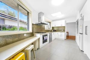 a kitchen with white appliances and a large window at Comfy Croydon Family Getaway Near Trails and Cafes in Ringwood North +7 photos