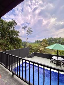 een balkon met een tafel, een parasol en een zwembad bij Deju Cabin with Private Pool & Mountain View in Cilama