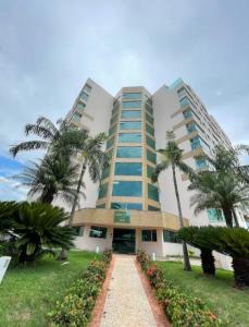 a building with palm trees in front of it at Studio Inn Rami in Uberlândia