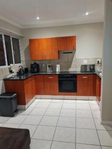 a kitchen with wooden cabinets and a black appliance at 1 Bedroom Luxury Apartment, Beacon Bay North, East London in East London +6 photos