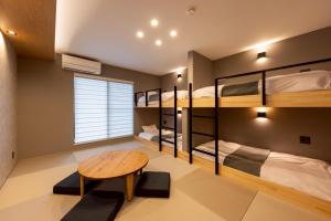een kamer met 3 stapelbedden en een houten tafel bij STAY THE RINKU BAY Apartment Hotel in Izumi-Sano