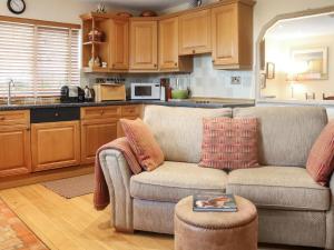 a living room with a couch and a kitchen at Snowdrop Cottage in Treffynnon 