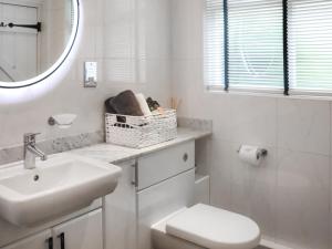 a bathroom with a sink and a toilet and a mirror at Snowdrop Cottage in Treffynnon  +3 photos