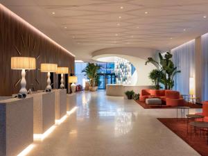 a lobby of a hotel with orange chairs and tables at Mövenpick Hotel Basel in Basel