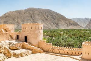 un castillo en el desierto con una montaña en el fondo en Maison Miraj Hostel, en Mascate