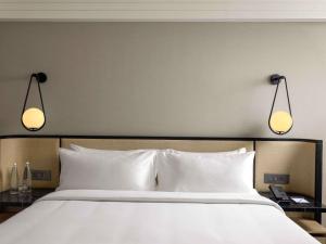 a large bed with two lights above it at Pullman Chennai Anna Salai - Premium Brand By Accor in Chennai