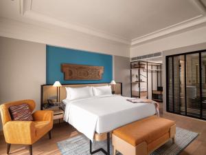 a bedroom with a large white bed and a chair at Pullman Chennai Anna Salai - Premium Brand By Accor in Chennai