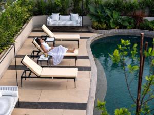 a woman laying on a chair next to a swimming pool at Pullman Chennai Anna Salai - Premium Brand By Accor in Chennai