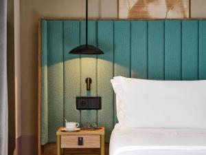 een slaapkamer met een bed en een nachtkastje met een lamp bij Hotel Giacomo Morra Alba - Handwritten Collection in Alba