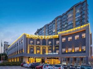 a large building with cars parked in a parking lot at Lavande Hotel Changchun Gaoxin Jilin University in Changchun