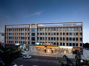 a large building with a car parked in a parking lot at Vienna Hotel Guangzhou Yonghe Development Zone in Guangzhou