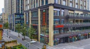 a building on a city street with tall buildings at Vienna Hotel Chongqing Yangjiaping Pedestrian Street Light Railway Station in Chongqing