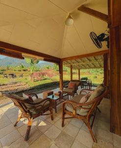 Un porche con sillas y vista a un campo. en Pondok Sitinggil Muncul, en Muncul