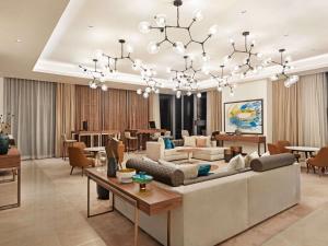 a living room with a large couch and a chandelier at Novotel Dubai Gold District in Dubai