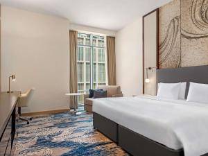 a hotel room with a large bed and a desk at Novotel Dubai Gold District in Dubai +101 photos