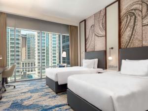 a hotel room with two beds and a large window at Novotel Dubai Gold District in Dubai