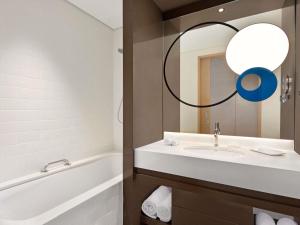 a bathroom with a sink and a tub and a mirror at Novotel Dubai Gold District in Dubai +102 photos