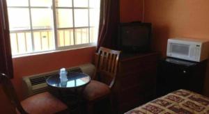 una pequeña mesa y sillas en una habitación con ventana en Coast Motel, en Signal Hill