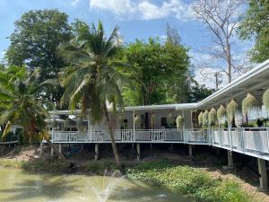 a house with a palm tree next to a body of water at Pun's Garden Home in Ban Sao Thong