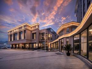 a large building with a sunset in the background at Nanjing Grand Da Qiao Hotel in Nanjing